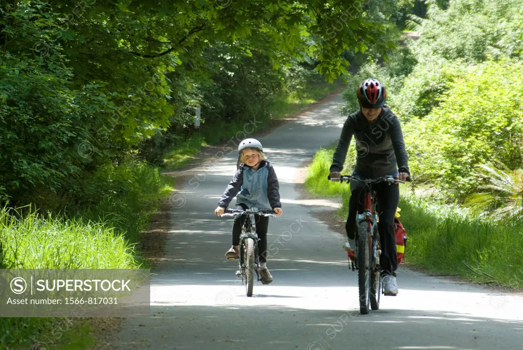 a nine year old boy and a middle-aged woman ride bicycles on a country road on Saltspring Island, Gulf Islands, BC, Canada