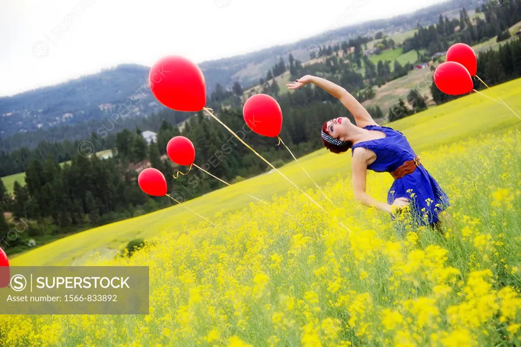 A beautiful young female in a canola field with balloons near Spokane, Washington, USA.