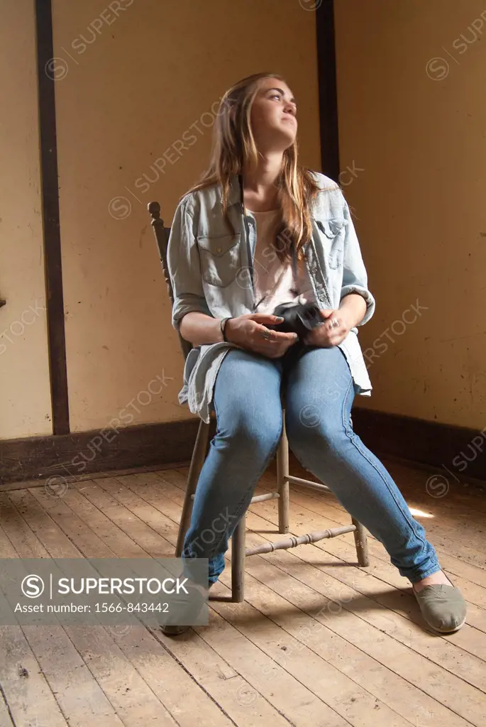15 year old girl sits in an old abandoned house with her camera