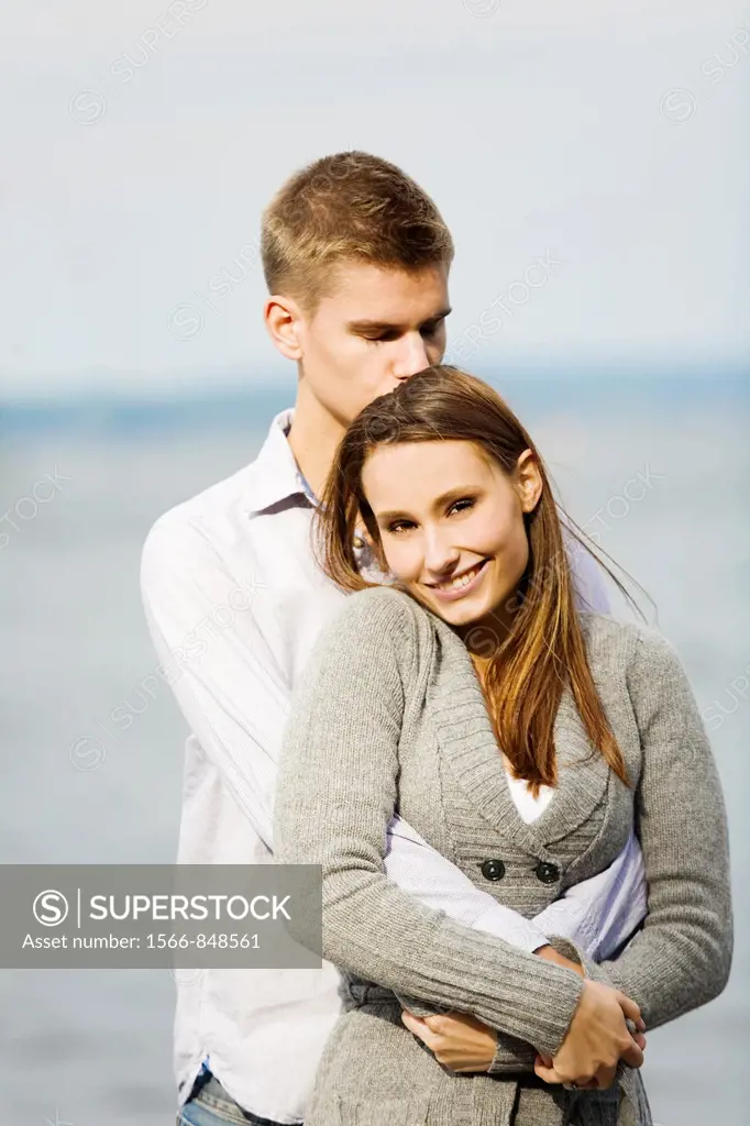 Portrait of a young couple holding and kissing by the sea