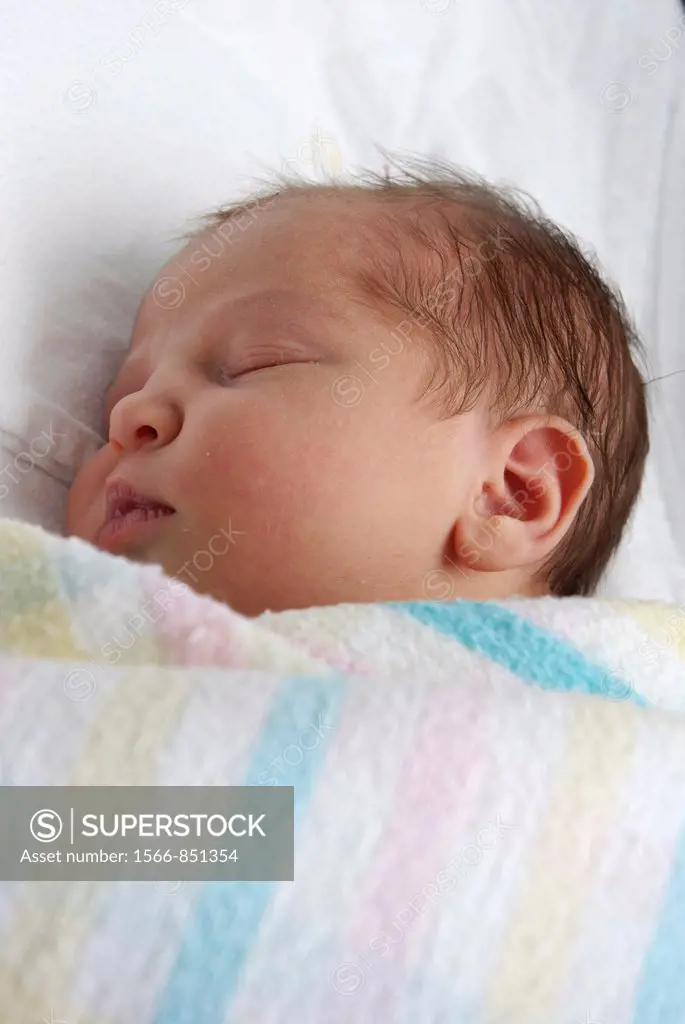A newborn baby asleep in swaddling blankets