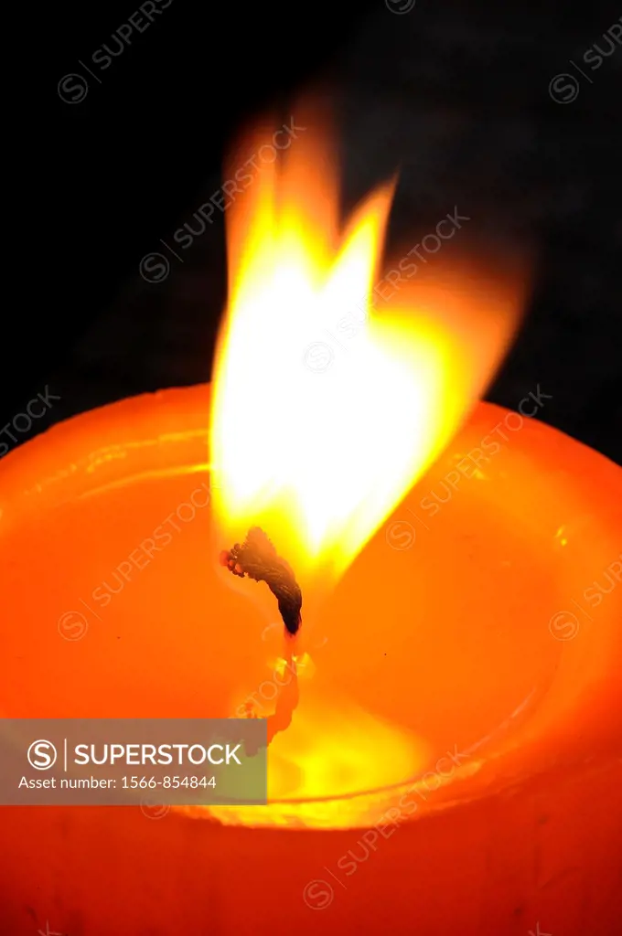 Detail of a candle flame with waving in the air on a dark background