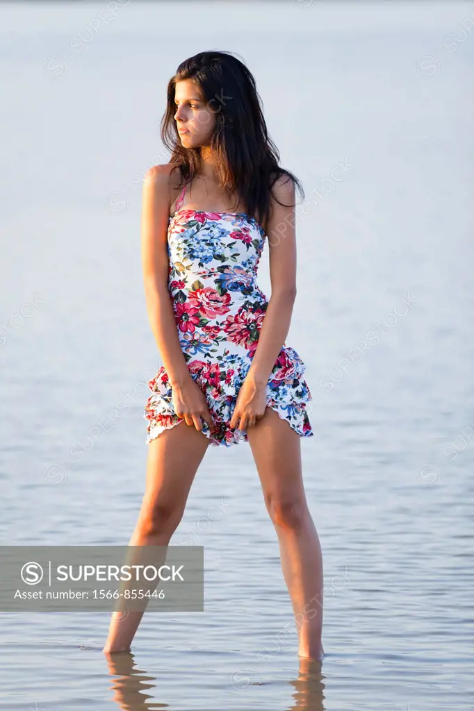Attractive young woman hiking up her Summer dress exposing legs