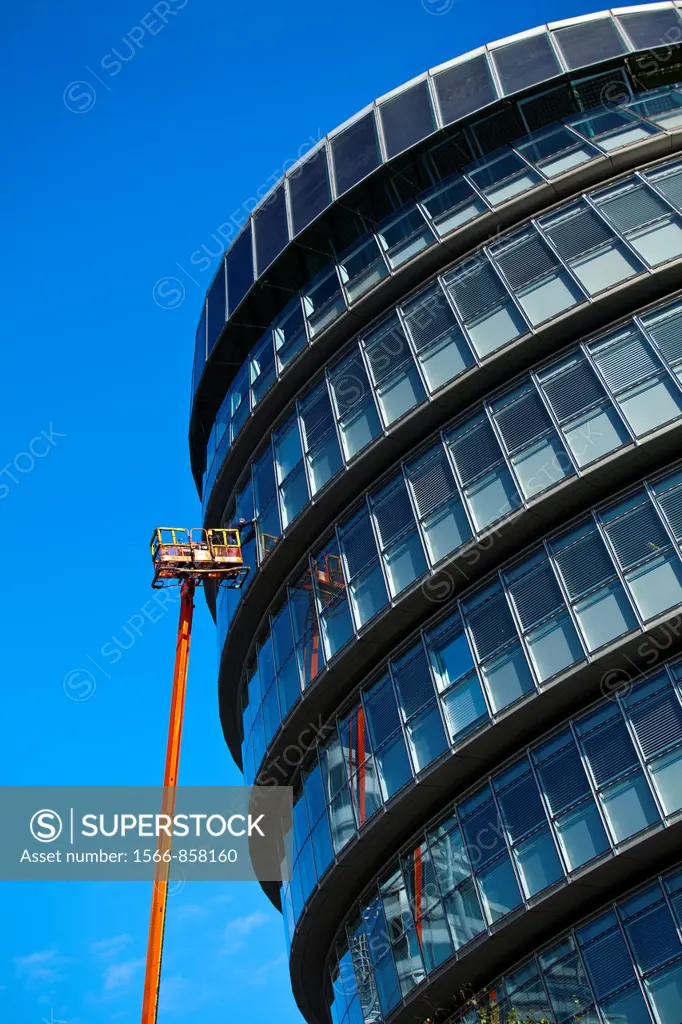 England, London, Southwark  Workman performing maintenance from a cherry picker on a window of the London City Hall located near Tower Bridge on the R...