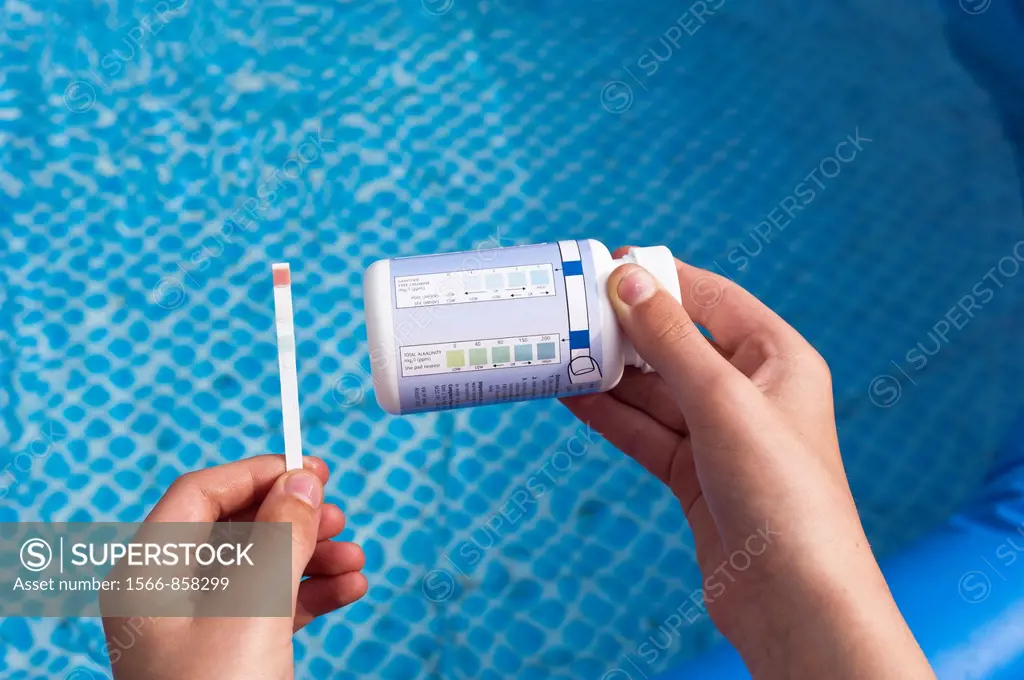 Testing a swimming pool with a testing stick dip test for alkalinity , chlorine and PH levels