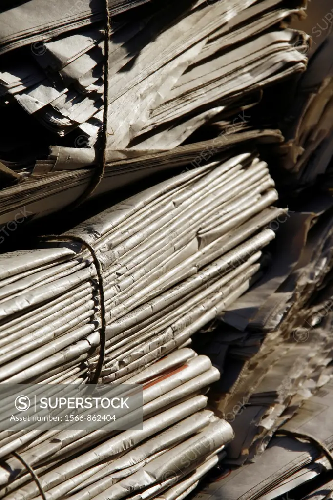 pile of old used newspapers left in street road in city town