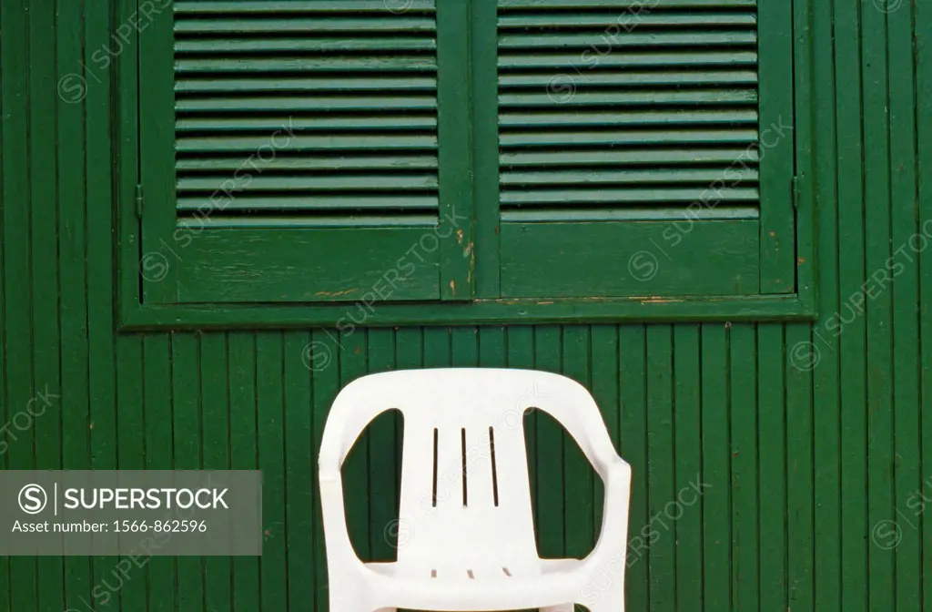 White Plastic Chair in front of Green Hut