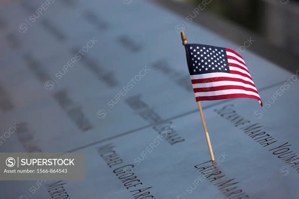 A small American flag left on the names inscribed in the perimeter of one of the pools at the National September 11 Memorial in New York City, New Yor...