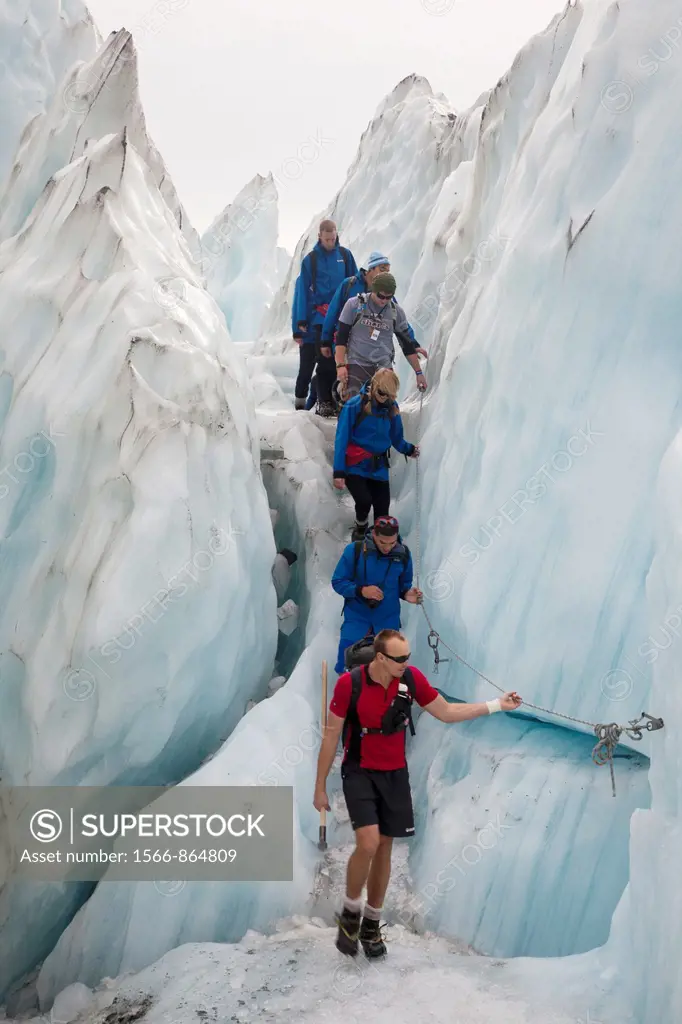 Guided tourist party wear crampons to walk through Franz Josef Glacier, Westland National Park, West Coast of South Island, New Zealand