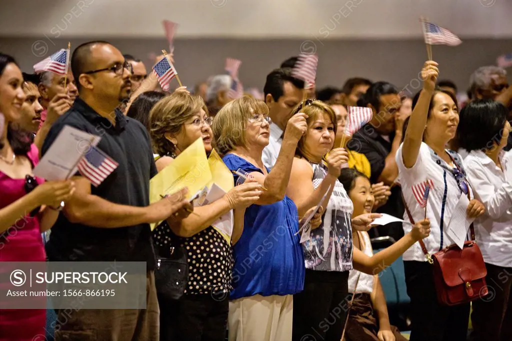 Immigrants of many ages and nationalities cheer and wave U S  flags after taking the oath of United States citizenship in Los Angeles