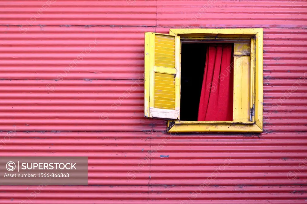 Window to the world: Red house of tin plates with one open, yellow window in El Caminito, La Boca, Buenos Aires, Argentina, South America