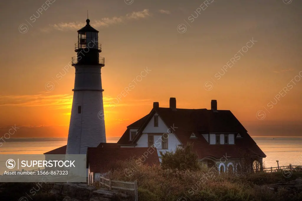 The rising sun behind the Portland Head Light, built in 1791, which protects mariners entering Casco Bay. The lighthouse is located in Fort Williams P...