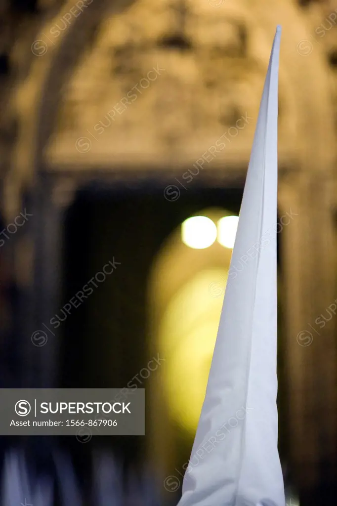 Hooded penitent entering Seville´s cathedral, Holy Week, Spain