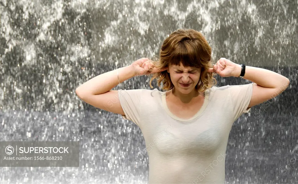 face of exhauted young woman in front of noisy falling water