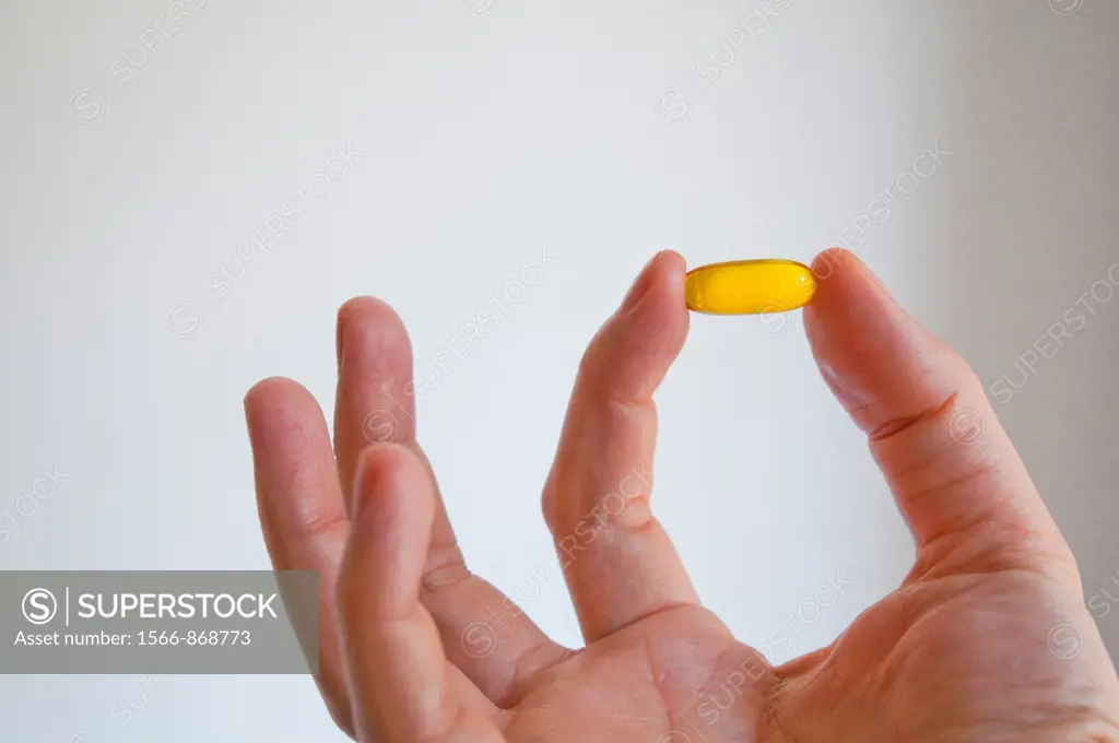 Man´s hand holding a primrose pill. Close view.