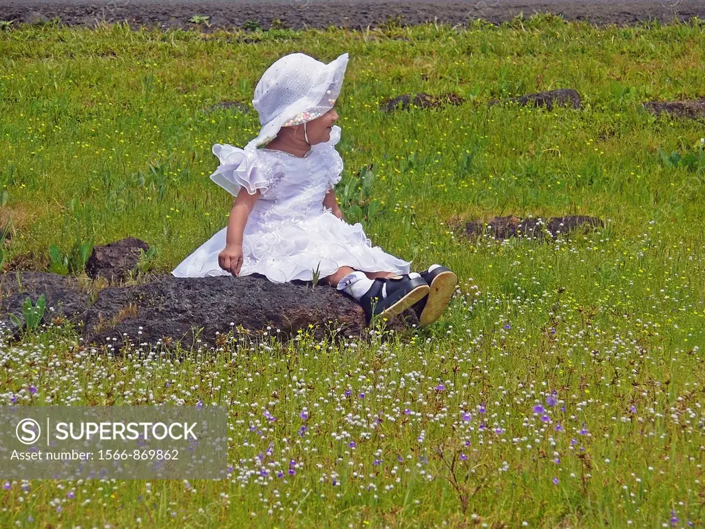 Small girl seating at green heaths, Plateau of flowers, Kaas, Satara, Maharashtra, India