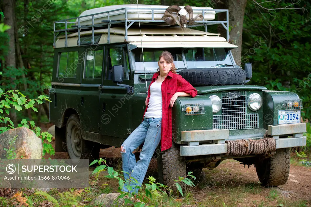 Female model in forest with 1966 Land Rover Series 2A 109 near Lewiston Maine USA