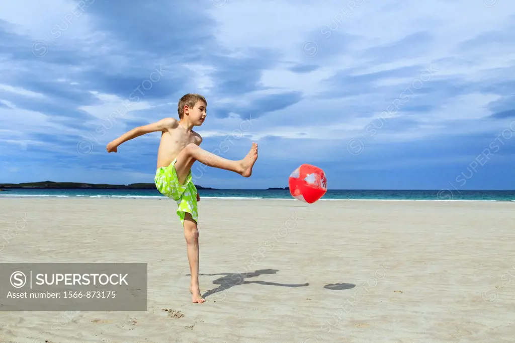 boy playing on sandy beach, Sutherland, Scotland