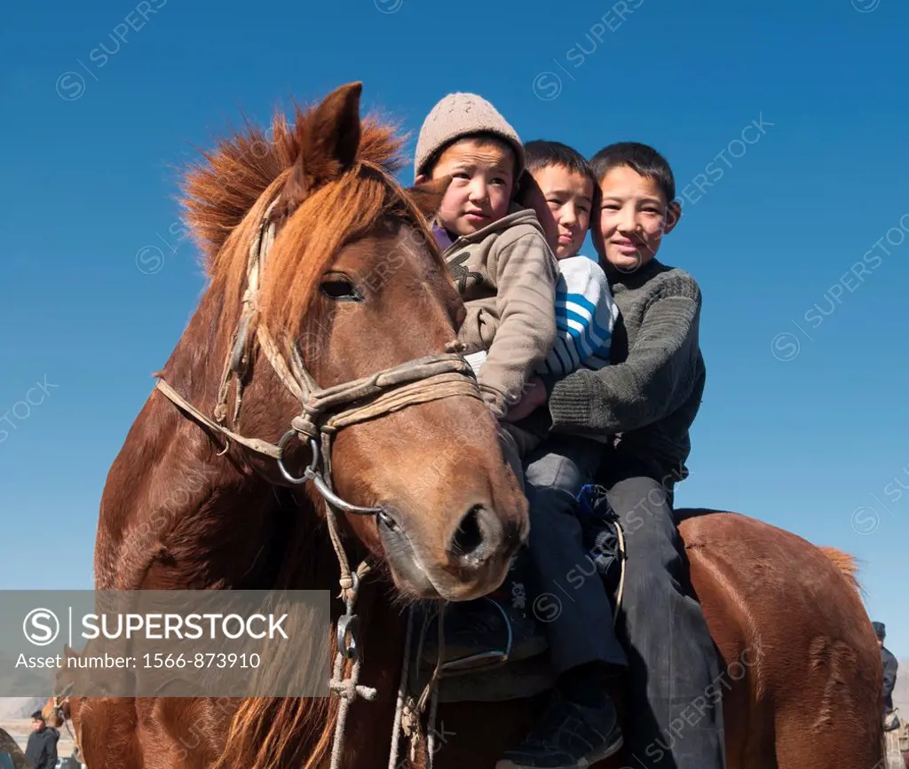 portrait of three ethnic Kazakh boys on horseback in the Altai Region of Bayan-Ölgii in Western Mongolia