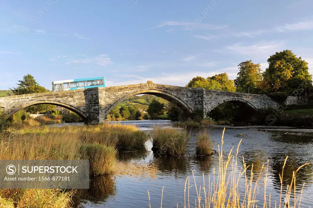 Arriva bus crosses the River Conwy on the Pont Fawr bridge in the old town of Llanrwst in the Conwy Valley, Gwynedd, Wales, UK
