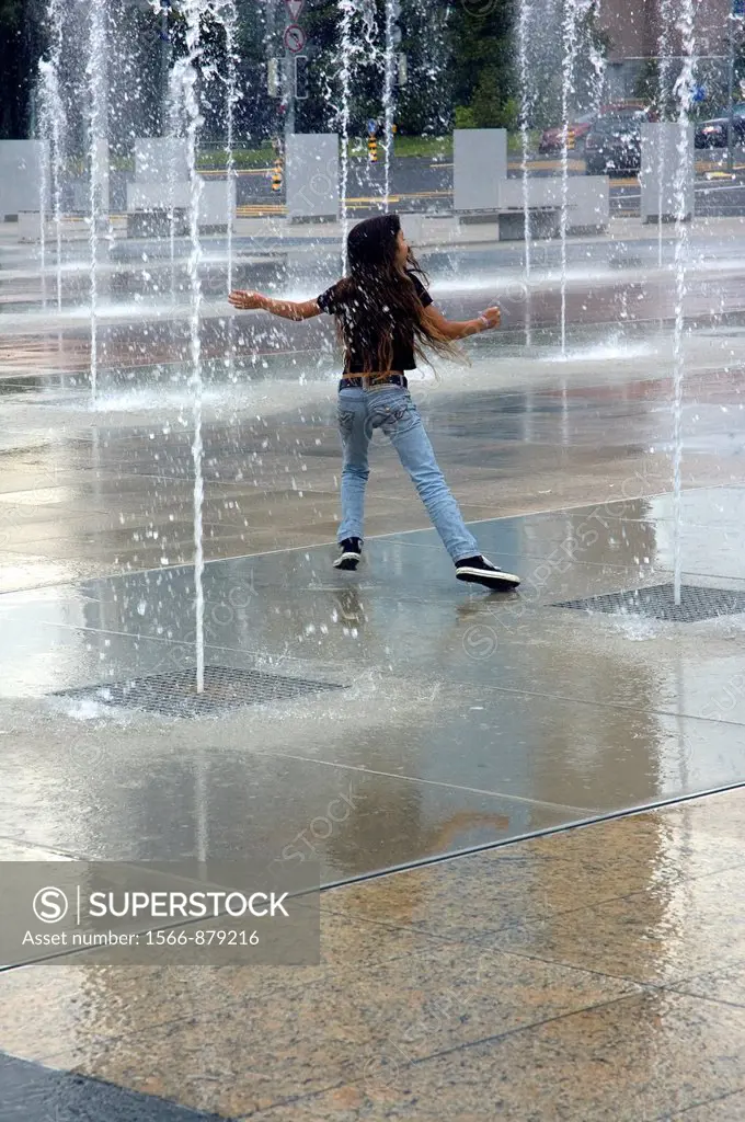 girl enjoying water drops falling down from fountains around, front of Palace of Nations, Geneva, Switzerland