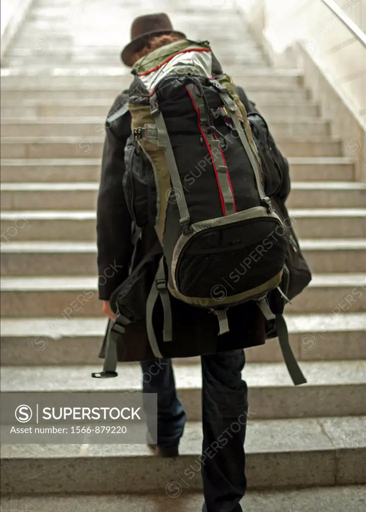 single man travelling with backpack climbing the stairs