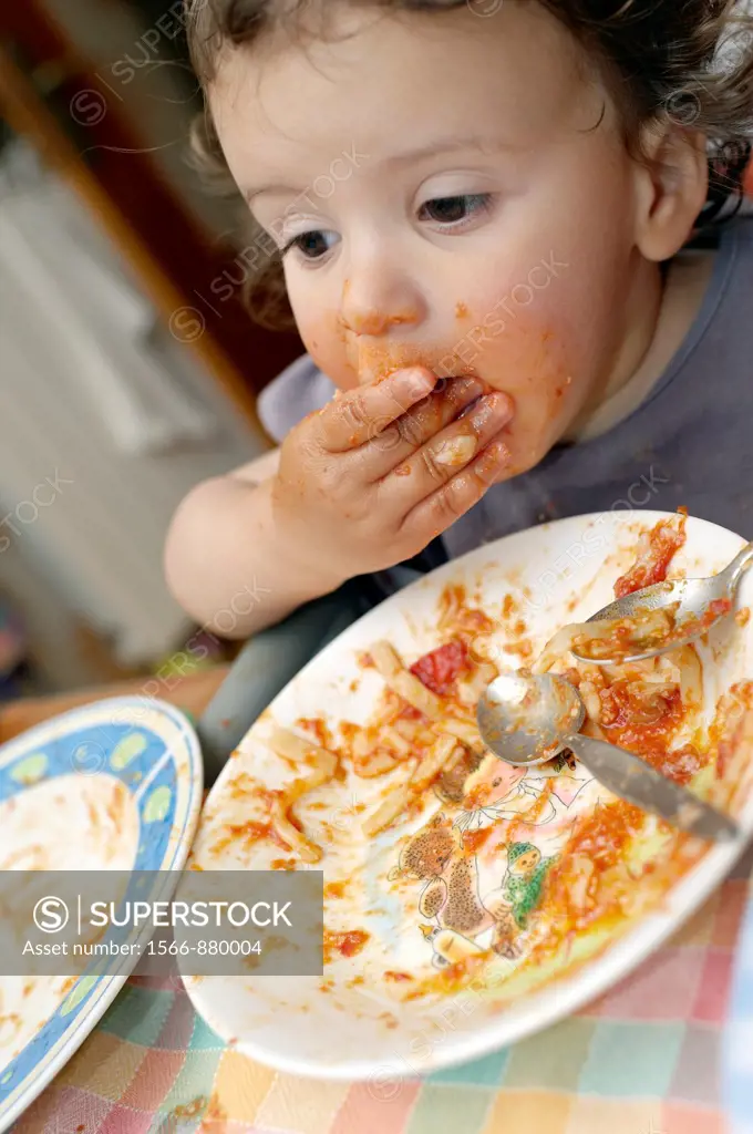 A seventeen months old baby girl eat tomato sauce paste with her hands  Selective focus on the mouth