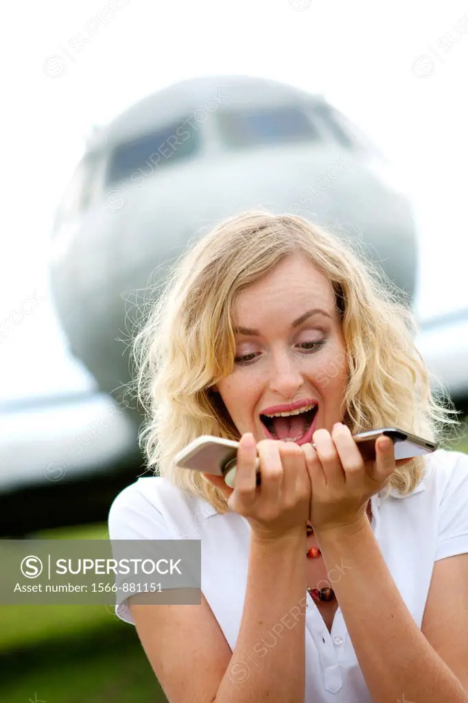 A business woman with two mobiles phones next to plane
