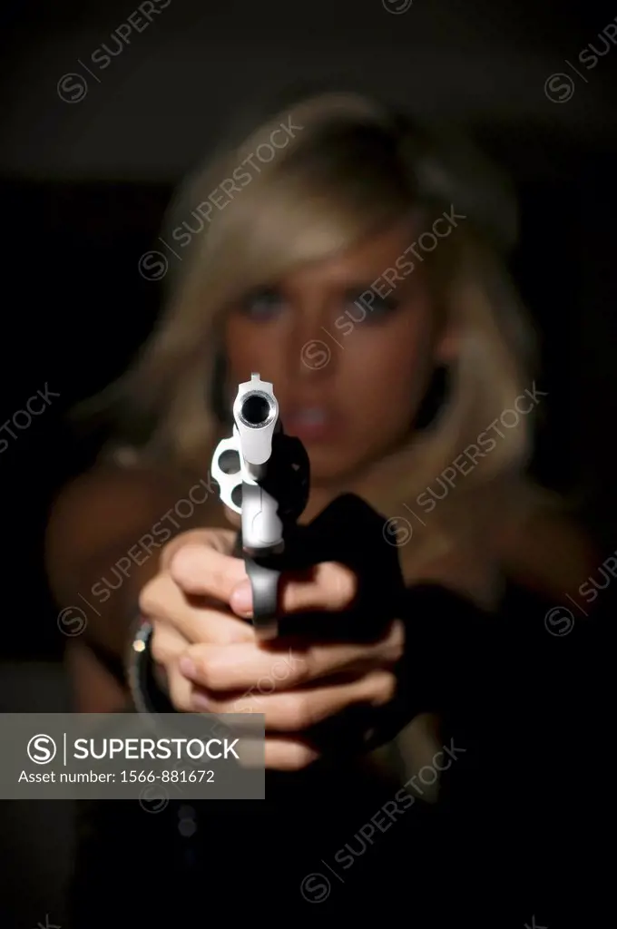 Woman in fear pointing a gun at viewer
