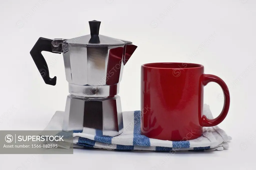 Detail photo of a simple coffee maker, percolator, and a cup upright on a dishtowel