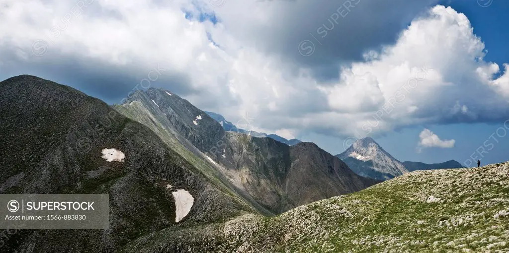 A lone hiker traversing the Pendadhaktilo ridge, the watershed of the Taygetos mountains with the peaks of Marmarokastro and Chalasmeno in the backgro...