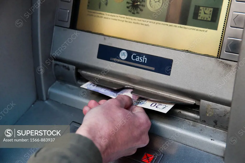 Detail of a hand withdrawing money from a cash machine.