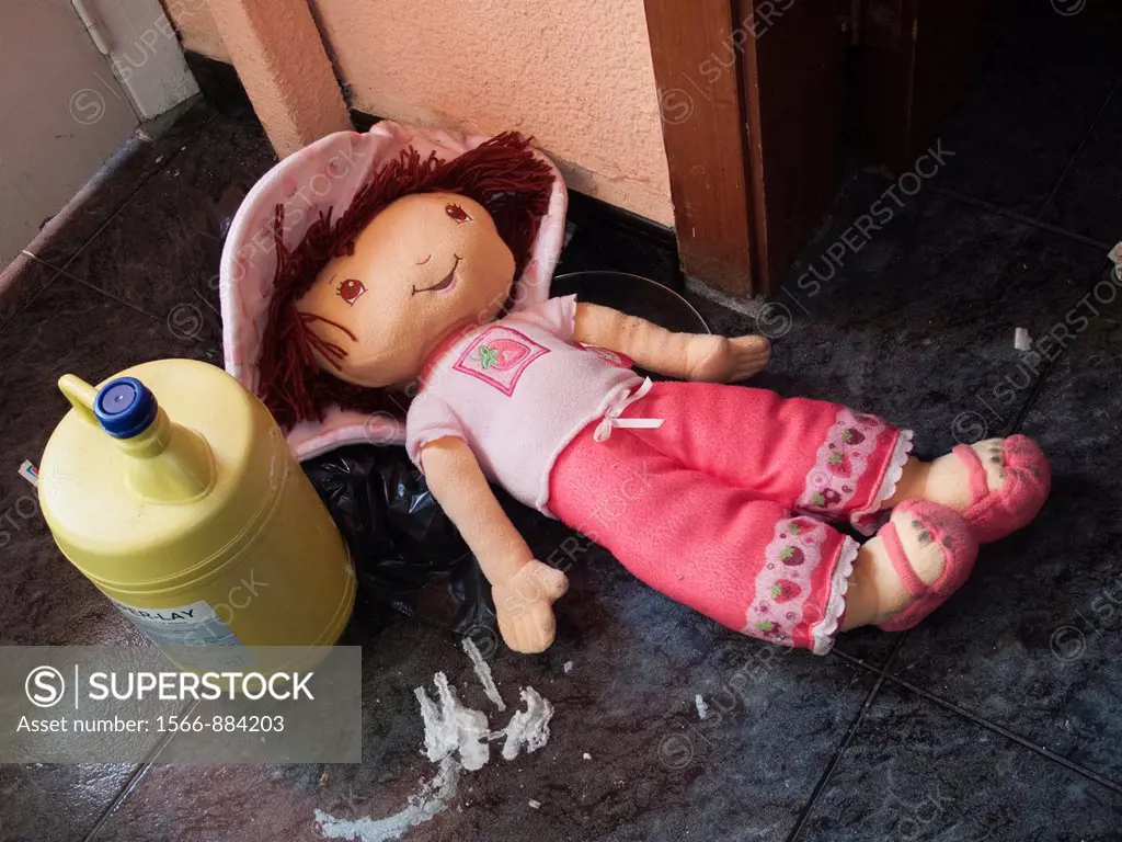 Abandoned doll in an empty house besides a leaking bleach bottle