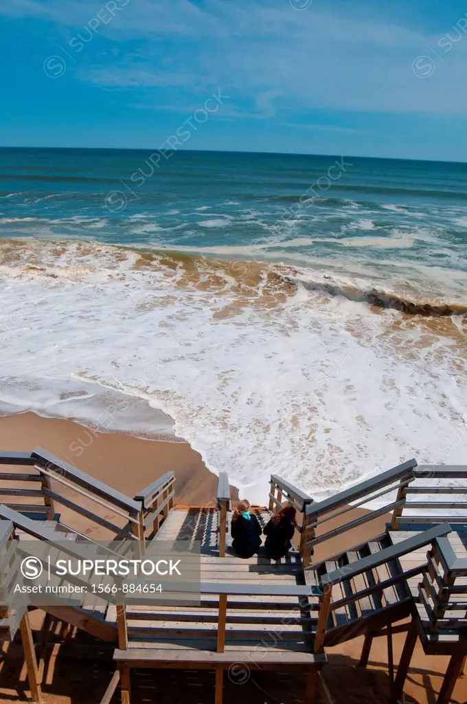 Two girls watch the waves sitting on stairs in Marconi beach, Cape Cod