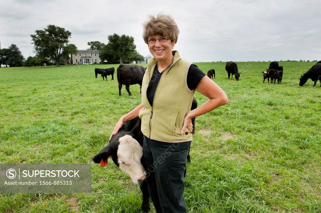 Woman standing in pasture with Angus beef cattle