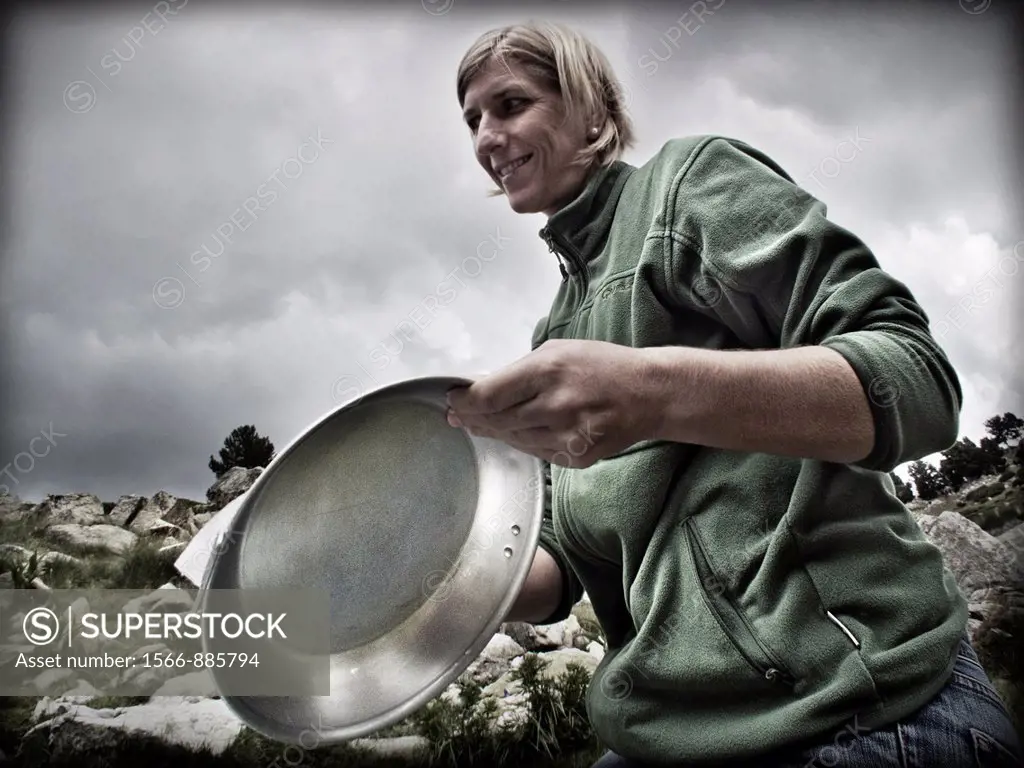 Young blonde woman preparing aluminum plates on the mountain.