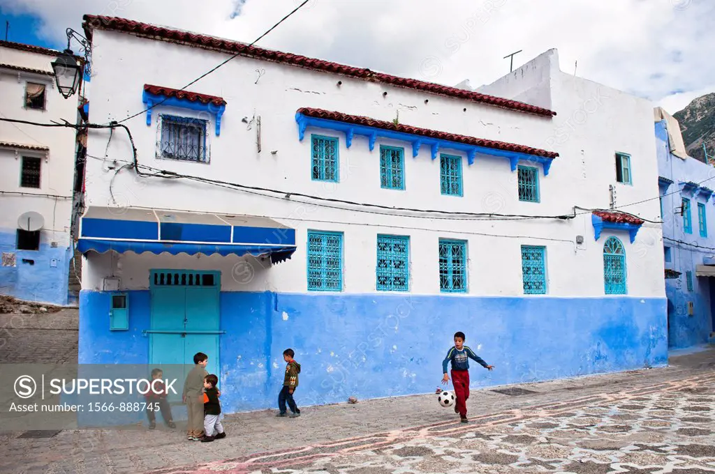 Kids playing footbal in the blue walled old medina of Chefchaouen, Morocco