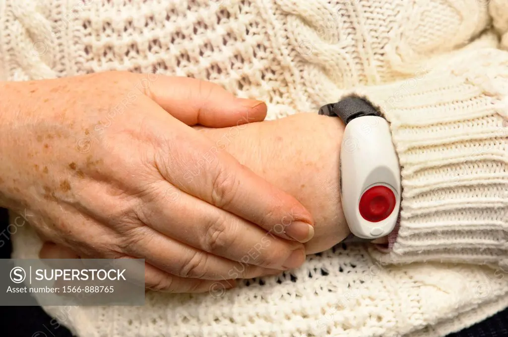 A senior elderly woman in her 70´s with a home alarm unit on her wrist for emergencies at home in England , Britain , Uk