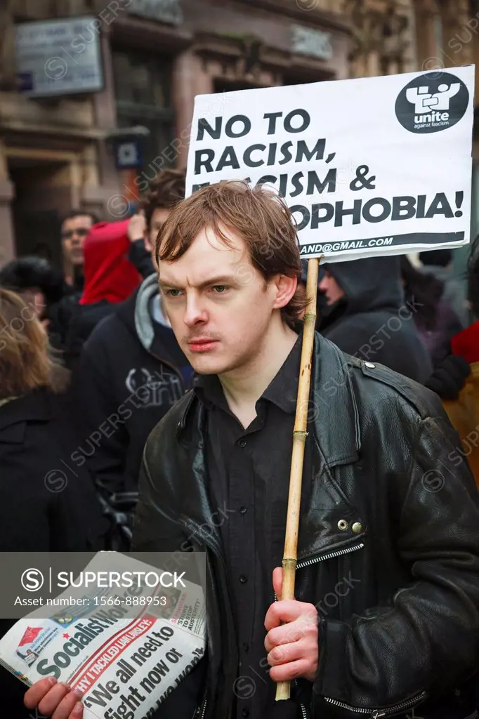 Young man carrying an anti-racism banner and selling ´The Socialist Worker´ while at a street demonstration, Glasgow, Scotland, UK