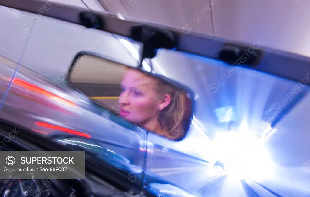 Young woman reflected in mirror driving through tunnel in sports car