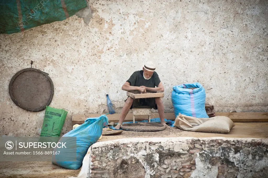 Old man selecting pigeon poo to soften the leatherat the Chouwara Tannery, Fez, Morocco
