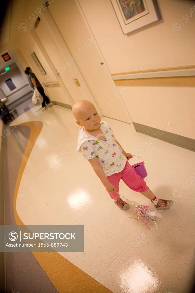 Portrait of a young girl with pediatric cancer leukaemia walking through the halls of a hospital  She has just been accessed through her port-a-cath s...