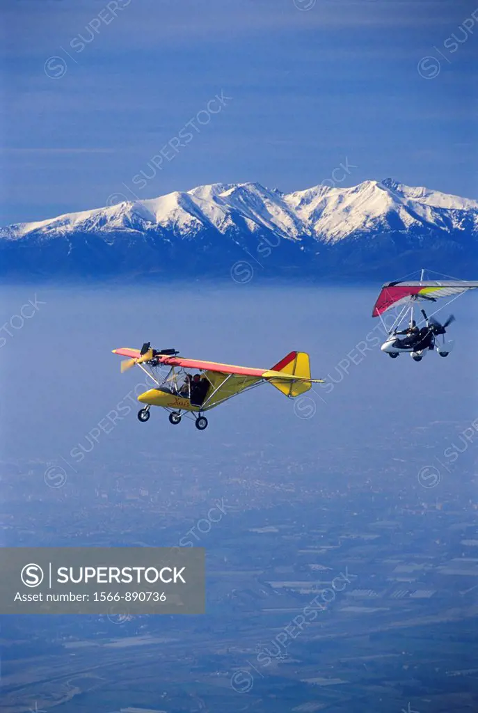 Ultra light planes flying in wintertime over thin clouds arround Torreilles  At background the snowed Canigou peak 2784 m  Orientales Pyrenees, Langue...