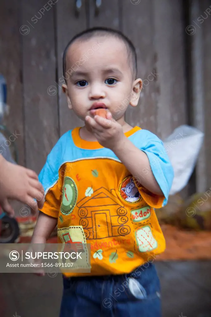 Malay boy eating sausage at Siniawan Bazaar, Sarawak, Malaysia