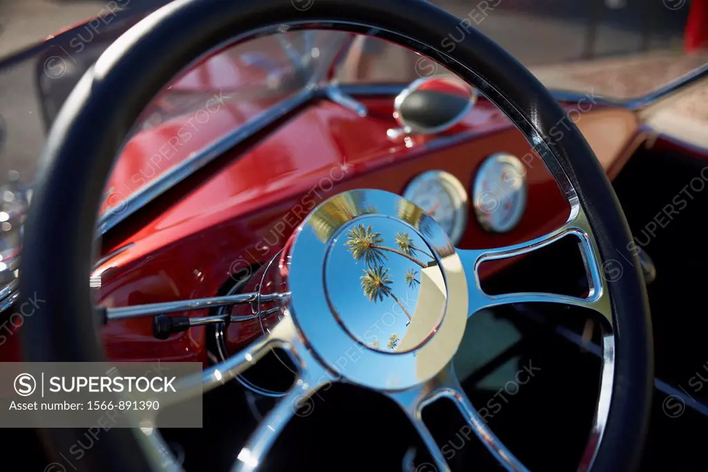 palm trees reflected in the steering wheel of a vintage automobile