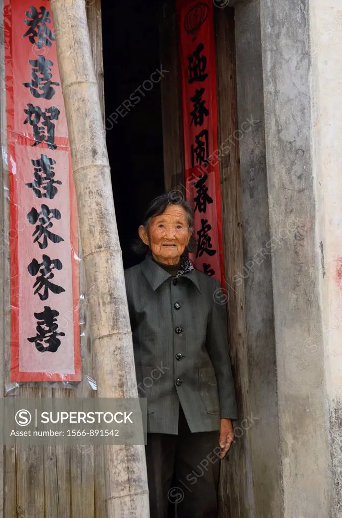 Elderly woman standing in doorway in ancient Shangshe village on Fengle lake Huangshan China