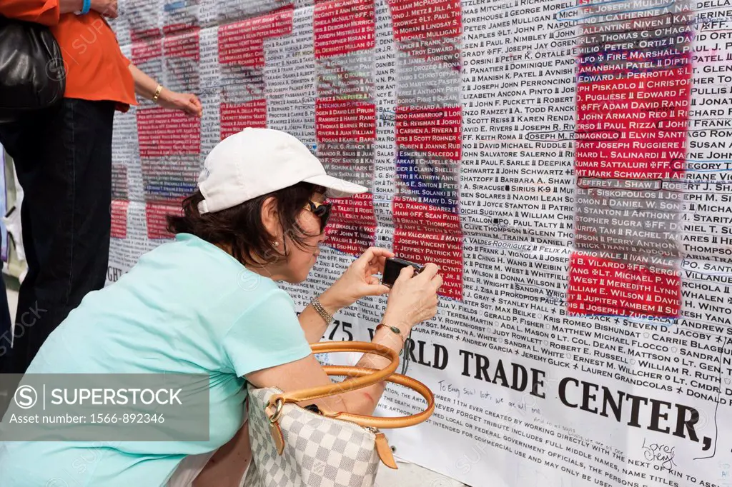 A woman photographs a name on the list of those who perished in the 9/11 terrorist attack of the World Trade Center. The list is posted on Greenwich S...