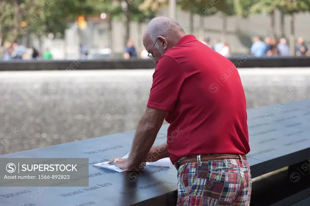 A visitor creates a rubbing of one of the names at the National 9/11 Memorial in New York City, New York, USA