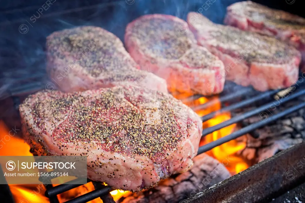 Beef Ribeye Steaks grilling over hot fire