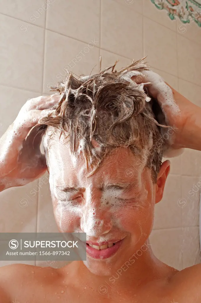 a teenage boy washing his hair in the shower